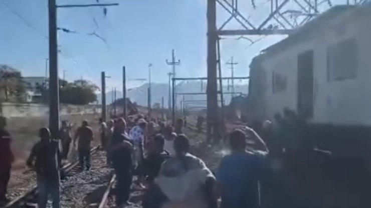 Passageiros caminham pelos trilhos do trem após incêndio no Rio