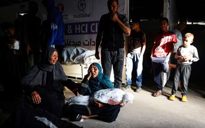 Mulher palestina segura nos braços o corpo amortalhado de um menino morto em um bombardeio israelense, em uma clínica em Rafah, sul da Faixa de Gaza, em 26 de maio de 2024