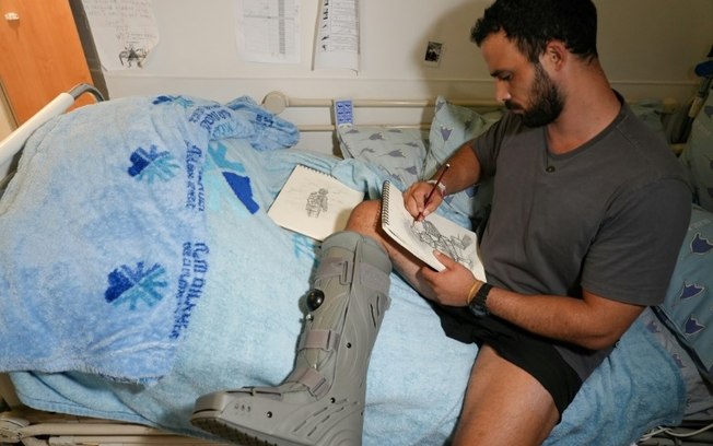 Barak, um soldado israelense ferido em Gaza, desenha na cama do hospital Ichilov em Tel Aviv, 22 de julho de 2024