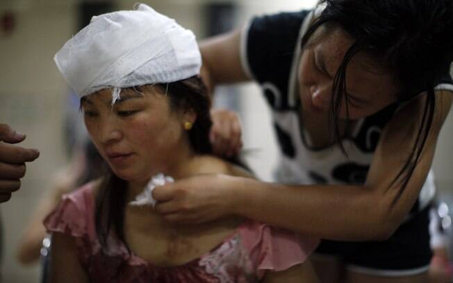 Mulher ferida é tratada dentro de hospital após explosões em Tianjin, China (13/08). Foto: AP