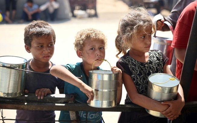 Crianças aguardam a distribuição de alimentos em um campo para deslocados em Khan Yunis, sul da Faixa de Gaza, em 11 de junho de 2024