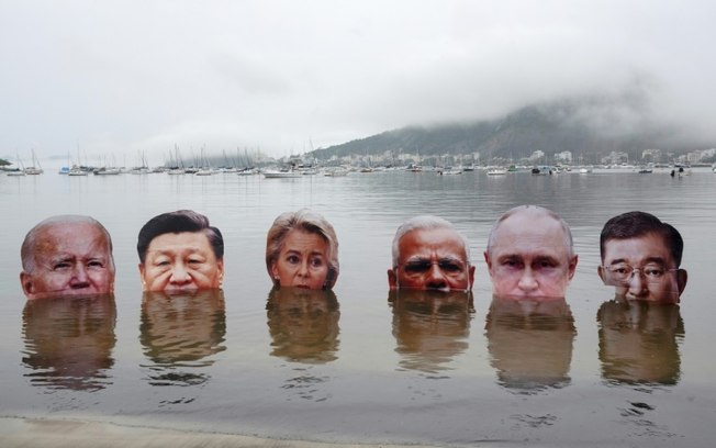 Retratos gigantes dos principais líderes mundiais participantes da cúpula do G20 são colocados na água por indígenas em uma praia do Rio de Janeiro, em 18 de novembro de 2024, em protesto contra o que consideram uma falta de liderança para proteger o meio ambiente