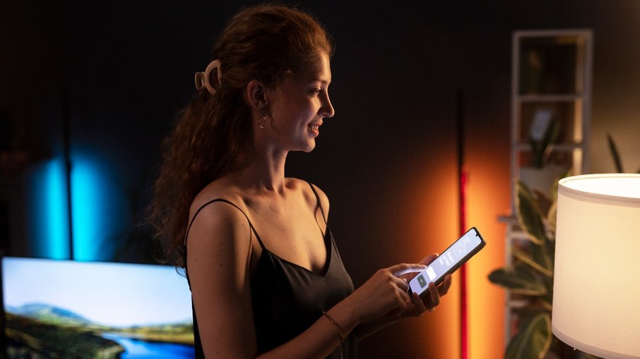 Mulher controlando a iluminação da sala a partir de um smartphone 