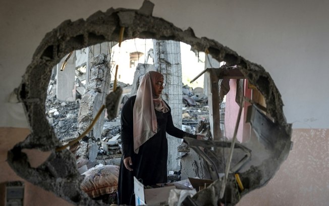 (20 abr) Mulher observa o que restou de sua casa, após bombardeio israelense em Rafah