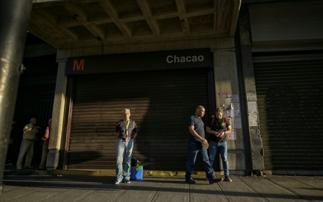 Várias pessoas passam na entrada de uma estação do metrô de Caracas, no dia 30 de agosto de 2024, após o apagão na Venezuela