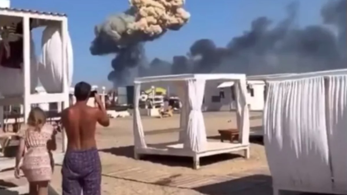 Banhistas observam coluna de fumaça após explosões na base de Novofeodorivka, na Crimeia 