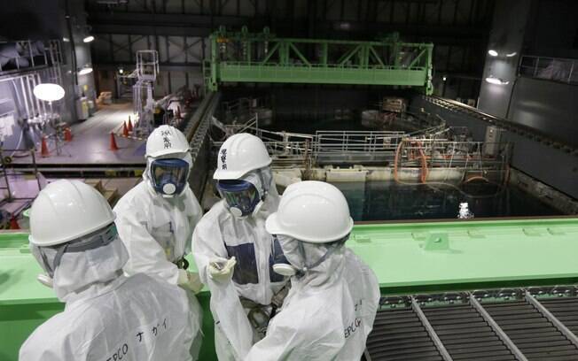 Protegidos, funcionários analisam situação dos combustíveis no reator número 4 de Fukushima, em novembro de 2013