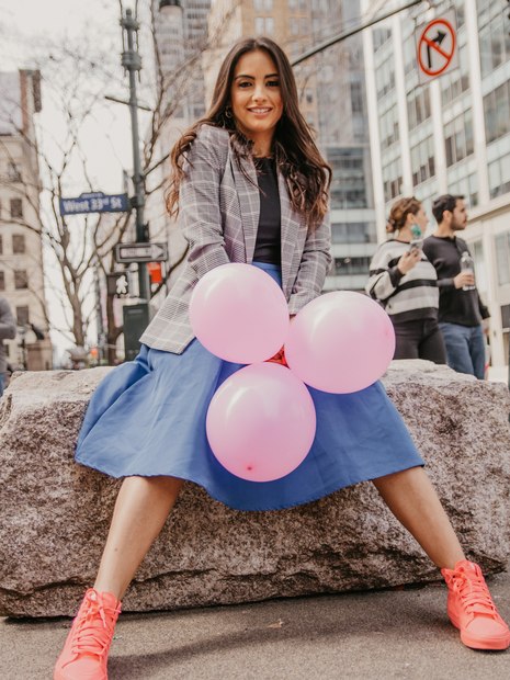 Amanda Lima sentada, segurando três balões rosas