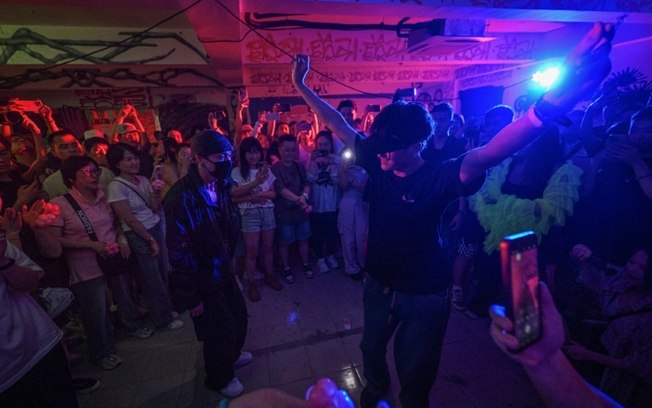 Uma mulher surda (à direita) dança na frente do rapper chinês Zhang Yixin durante uma festa em uma boate em Xangai, em 29 de junho de 2024