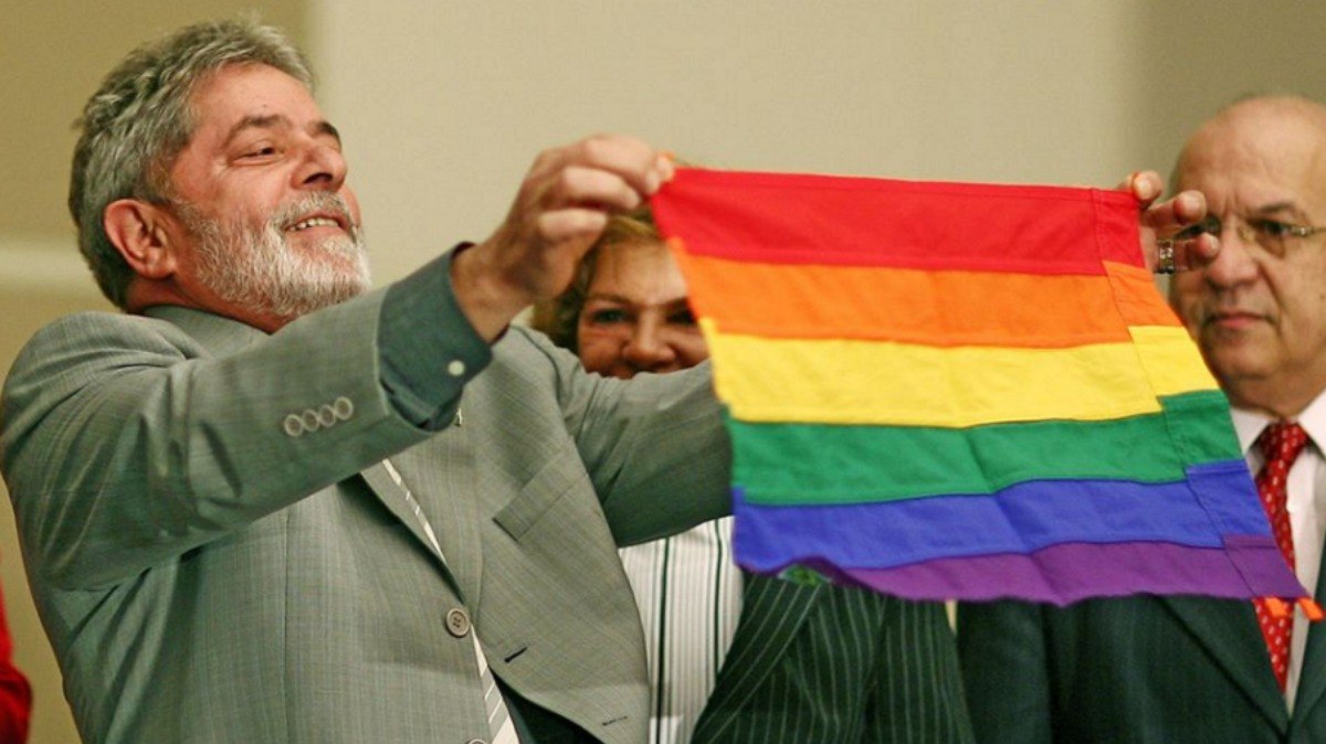 O então presidente Lula da Silva segurando uma bandeira da comunidade LGBTQIAP+ durante a a abertura da 1ª Conferência Nacional de Políticas Públicas e Direitos Humanos LGBT, em 2008.
