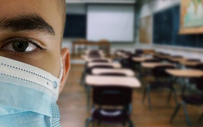 Pessoa em sala de aula vazia utilizando máscara