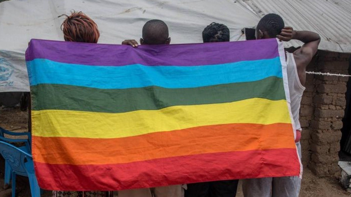 Manifestantes ugandenses pró-LGBT com bandeira do movimento queer