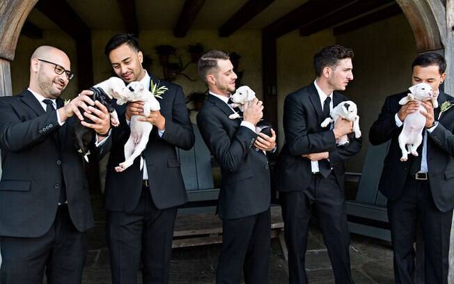 O noivo e os padrinhos também tiraram fotos para o ensaio de casamento segurando os filhotes de cachorrinhos 