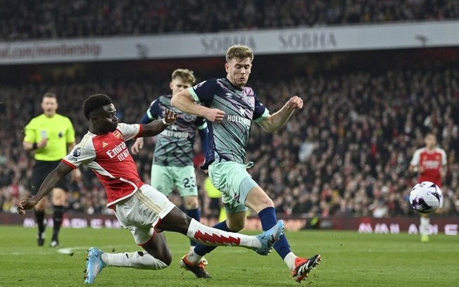  Saka (de vermelho)  tenta o cruzamento para o Arsenal. Mas é bem marcado pela defesa do Brentford