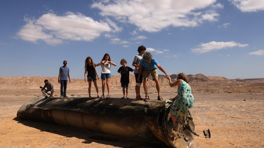 Pessoas em cima dos restos de um míssil iraniano no deserto de Negev, perto de Arad, em 2 de outubro de 2024, após um ataque de míssil iraniano contra Israel.