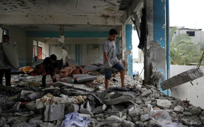 Palestinos observam escola da UNRWA atingida por bombardeio israelense em Gaza