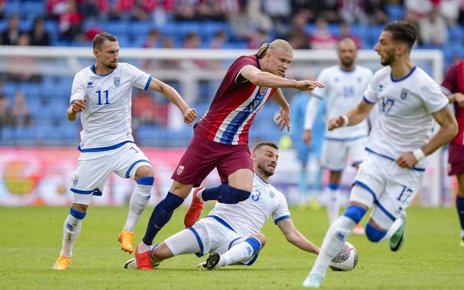 Haaland em disputa de bola com jogadores de Kosovo - Foto: Fredrik Varjell/AFP via Getty Images