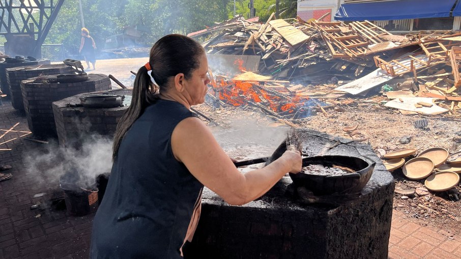 Artesã da Associação de Paneleiras de Goiabeiras pintando a panela assada com o líquido do Mangue Vermelho