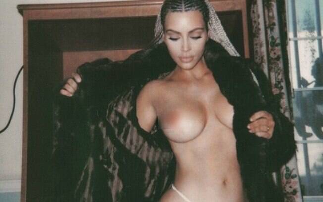 Usando somente um fio dental e casaco aperto  Kim Kardashian mostra os seios na web
