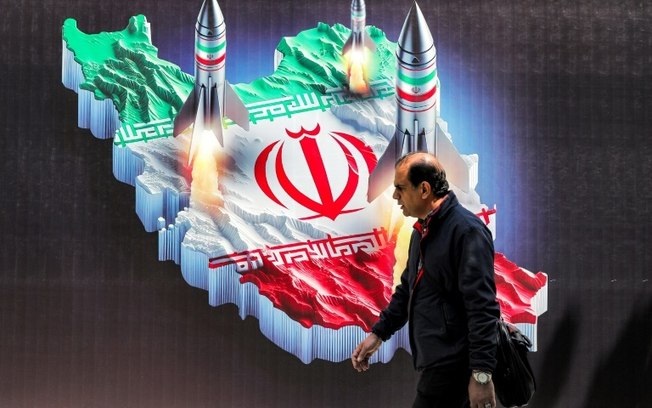 Homem passa por cartaz com o mapa do Irã no centro de Teerã, em 15 de abril de 2024