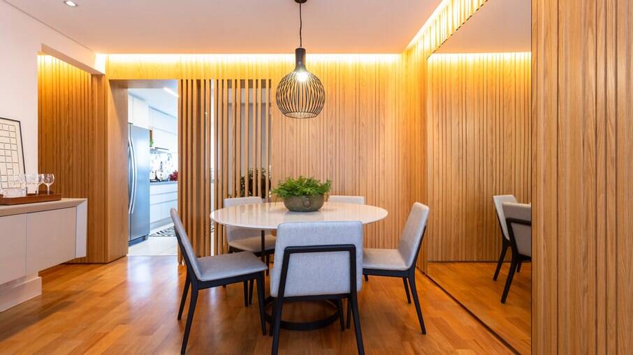 Uma sala de jantar também se beneficia do uso de fitas de LED, e a madeira tem sua textura acentuada pela iluminação 