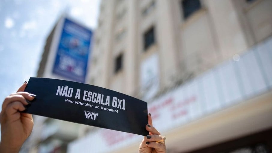 Trabalhadora de Fortaleza (CE) segurando cartaz do Movimento VAT durante ato na cidade