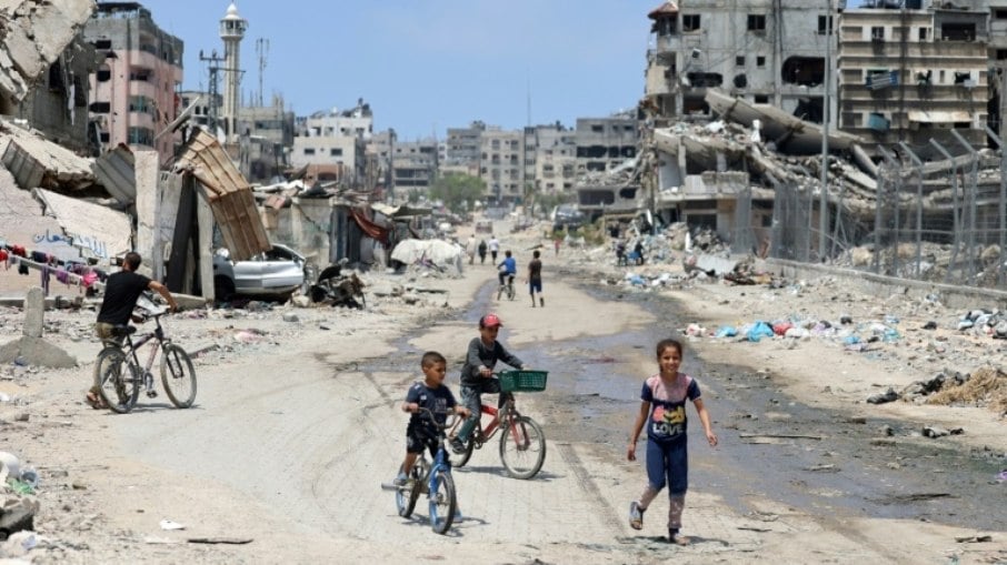 Crianças palestinas andam de bicicleta por uma rua devastada na Cidade de Gaza, 3 de maio de 2024