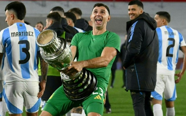 (ARQUIVO) O goleiro argentino Emiliano Martínez comemora com uma réplica do troféu da Copa América após vencer o jogo das Eliminatórias Sul-Americanas para a Copa do Mundo de 2026 contra o Chile, no estádio Más Monumental, em Buenos Aires, em 5 de setembro de 2024.