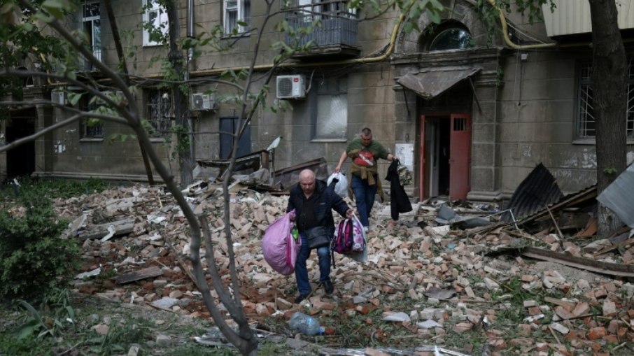 Moradores de um prédio atacado por mísseis na cidade ucraniana de Dnipro retiram seus pertences em 19 de abril de 2024