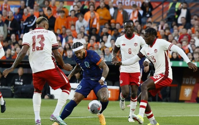 O atacante holandês Memphis Depay (C) disputa a bola com o zagueiro canadense Moise Bombito (dir.) no estádio de Kuip em Roterdã no dia 6 de junho de 2024.