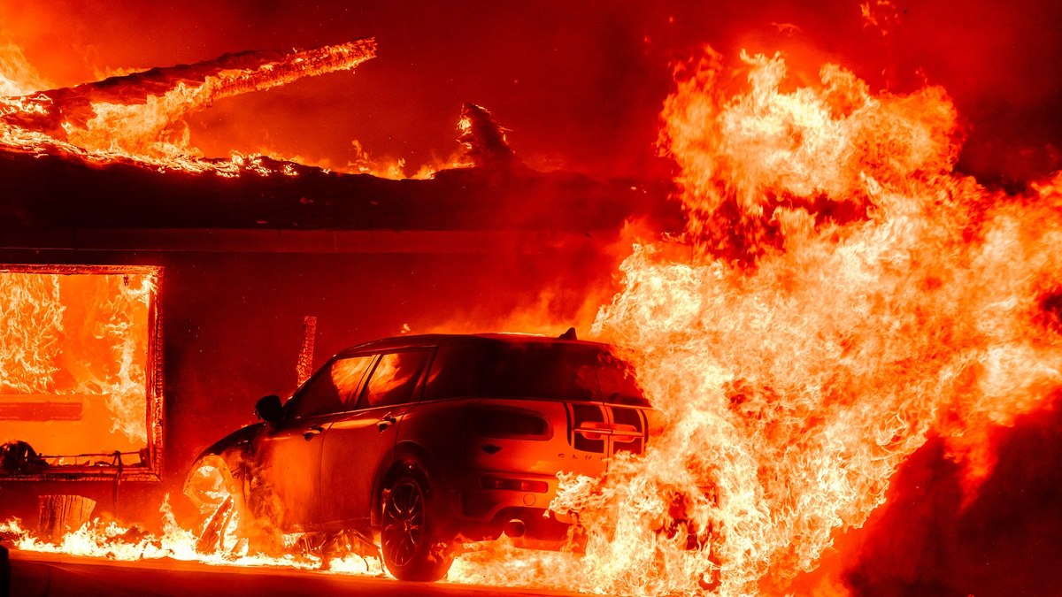 Um carro e uma casa queimam durante o incêndio de Eaton na área de Altadena, no Condado de Los Angeles, Califórnia, em 8 de janeiro de 2025