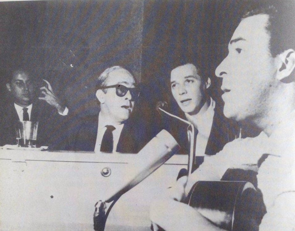 Curiosamente, os três se apresentaram no palco juntos apenas uma vez. Com o conjunto vocal Os Cariocas, Vinicius, Tom e João cantaram no restaurante Au Bon Gourmet, em Copacabana, em agosto de 1962. 
 Reprodução: Flipar