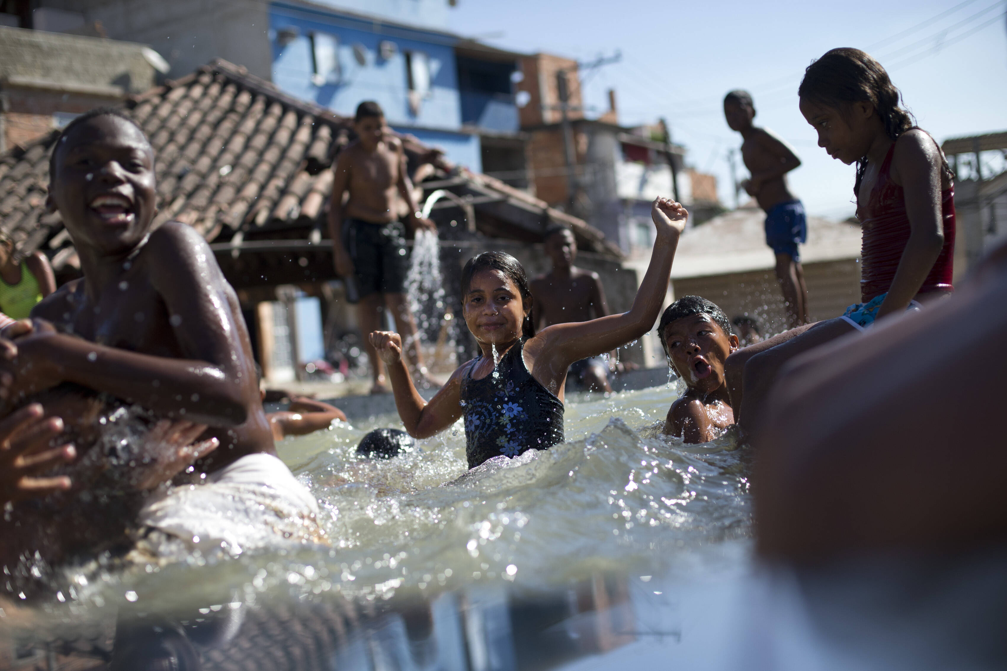 Crianças brincam numa piscina com água poluída em área sem tratamento de esgoto. Foto: Silvia Izquierdo/AP