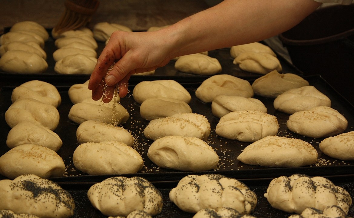 Algumas vezes, o pãozinho leva acréscimos de gergelim ou grãos, colocados antes do forno.  Reprodução: Flipar