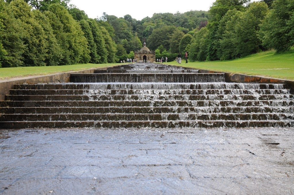 O jardim da residência do Duque de Devonshire é histórico, pois reúne itens de seis diferentes séculos. A estufa com espécies estrangeiras e a extensa cascata (foto) são detalhes realçados neste recinto da mansão.  Reprodução: Flipar