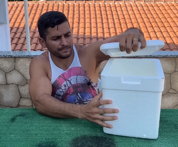 Em um vídeo tutorial no YouTube, o homem usa uma caixa de isopor como a base dessa solução improvisada, mas também menciona que um pote ou balde com tampa pode ser utilizado. 
