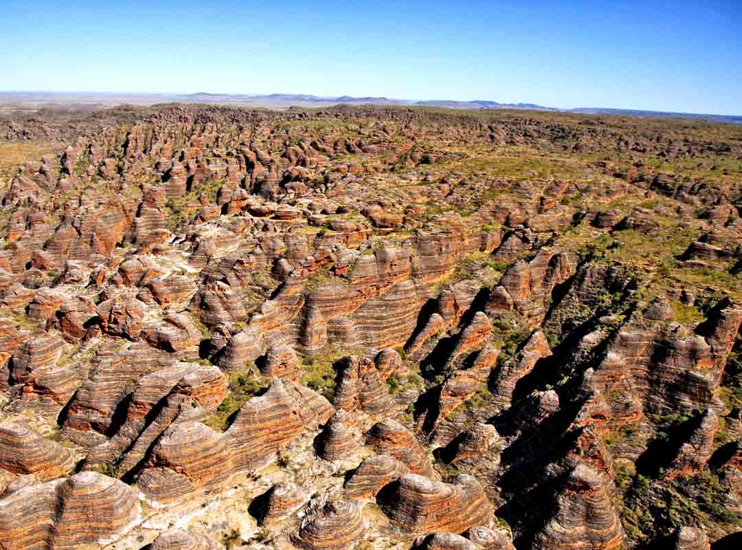 Cordilheira Bungle Bungle, Austrália: Localizada no Parque Nacional Purnululu, na região de Kimberley, na Austrália Ocidental, essa cordilheira é composta por domos de arenito laranja e preto que se erguem do solo do deserto. Reprodução: Flipar