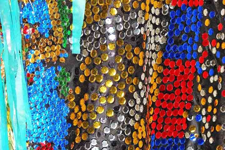 Entre os materiais mais utilizados nas fantasias de carnaval, sobretudo das escolas de samba, estão as lantejoulas. Elas são pequenas lâminas cintilantes, de metal ou vidro, com orifício para enfiar a linha, que servem para enfeitar vestidos ou bordados. Reprodução: Flipar