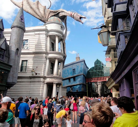 E a principal atração do Beco é o dragão no alto do Banco de Gringotts. A cada 10 minutos, ele solta fogo pela boca. Está sempre rodeado de centenas de visitantes.  Reprodução: Flipar