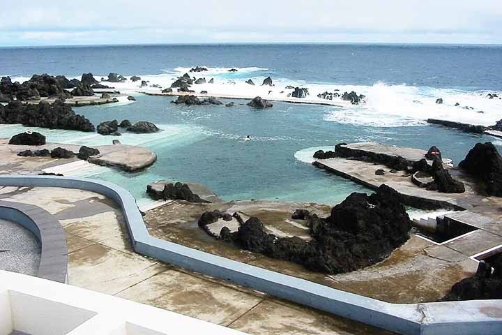 As Piscinas Naturais de Porto Moniz são um dos locais mais emblemáticos da Madeira. Criadas pela ação do vulcão, essas piscinas naturais são abastecidas pelas ondas do oceano, oferecendo uma experiência única de mergulho. Reprodução: Flipar