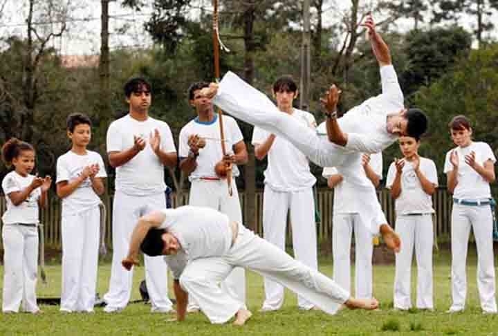 Capoeira- Tem raízes nas lutas e danças de origem africana, trazidas pelos escravos para o Brasil no período colonial. Sua técnica combina movimentos acrobáticos, ataques, esquivas e golpes de perna. Envolve música e ritmo, com som de atabaques.  Reprodução: Flipar
