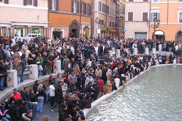 A tradição sugere que ao jogar uma moeda com a mão direita sobre o ombro esquerdo na Fontana di Trevi o turista terá sorte para voltar a Roma. 
 Reprodução: Flipar