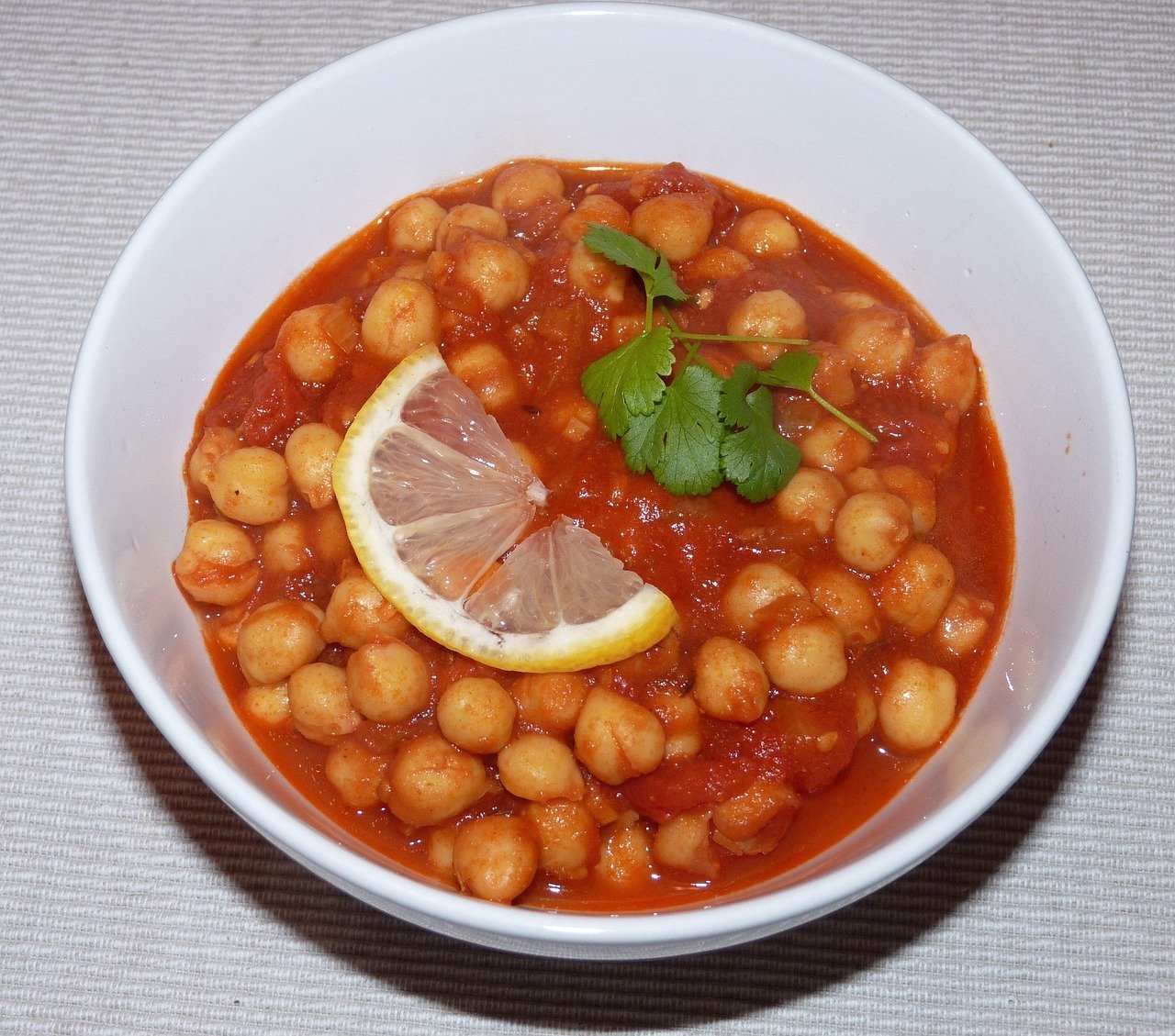 Chana masala é um prato indiano que utiliza grão-de-bico cozido em um molho rico em especiarias, como gengibre, alho, cominho e coentro. O resultado é um prato picante e aromático, geralmente servido com arroz ou pães. Reprodução: Flipar