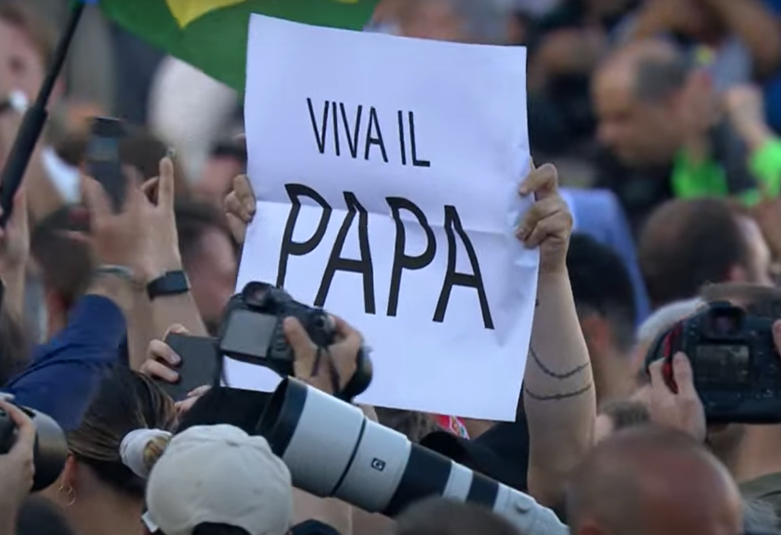 Pessoa com cartaz "Viva o papa" aguarda o anúncio na praça de S. Pedro. Foto: Reprodução/Vatican Media