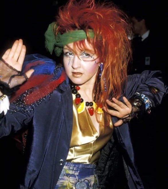 Com seu estilo único e chamativo, que combinava cores vibrantes, roupas excêntricas e penteados ousados, Cyndi Lauper se tornou um ícone cultural dos anos 80.  Reprodução: Flipar