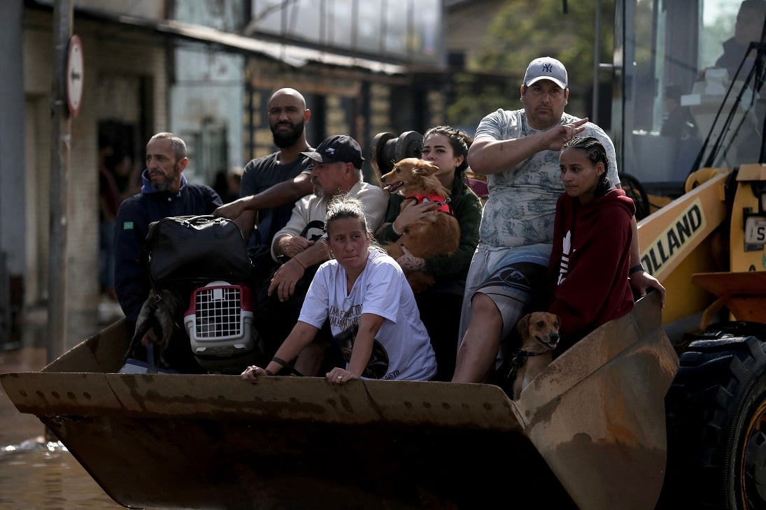 Pessoas são transportadas em retroescavadeira após serem resgatadas no bairro Sarandi, em Porto Alegre Anselmo Cunha/AFP - 05/05/2024