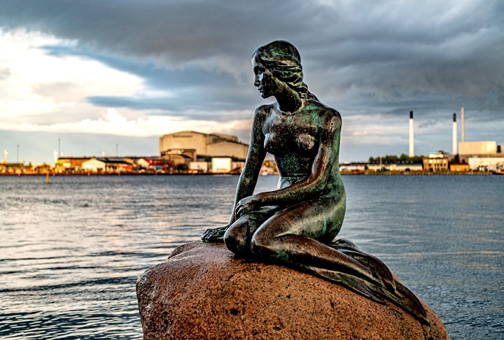 Pequena Sereia - Copenhague - Dinamarca. Estátua icônica situada no porto da cidade e inspirada no conto de Hans Christian Andersen, foi inaugurada em 1913. A escultura de bronze representa uma sereia com a parte inferior do corpo de peixe e a parte superior humana, sentada em uma rocha. Pequena em tamanho, a estátua é um popular ponto turístico e símbolo cultural da Dinamarca. Reprodução: Flipar