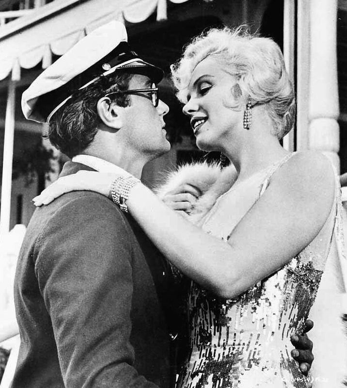 Os bastidores, porém, foram complicados. Ela se atrasava, esquecia as falas e precisava repetir cenas diversas vezes, causando irritação, principalmente, em Tony Curtis (na foto, em cena com Marilyn). Reprodução: Flipar