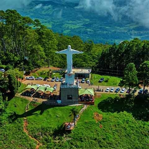 Situado no topo da Serra de São Domingos, o Parque do Cristo abriga o famoso Cristo Redentor de Poços de Caldas, que rende uma vista panorâmica da cidade. O local é acessível por teleférico, trilhas ou carro, e é muito procurado para contemplação, fotos e passeios ao ar livre. Reprodução: Flipar