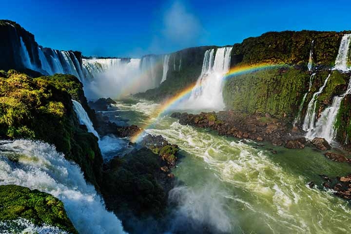 Cataratas de Iguaçu - Cidade: Foz do Iguaçu (Brasil) e Puerto Iguazú (Argentina) - O gugantesco volume de água que cai gera gotículas suspensas no ar. Com a luz solar incidindo nas partículas de água, arco-íris podem ser vistos com frequência. Reprodução: Flipar